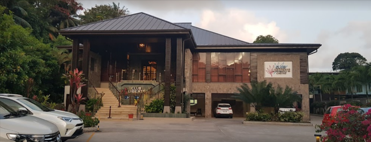 This is a photo of the exterior, parking lot and front entrance of Club Liberté Casino in Anse Soleil. Under the picture, on this page, you can read about the legal status of the various forms of Seychelles games of chance: internet lottery, digital bingo, electronic poker, sports betting, crypto wagering. There is also info about betting on blood sports, the licensing system, taxation regime, and you can find a list of licensed online gambling websites, which accept Seychellois players.