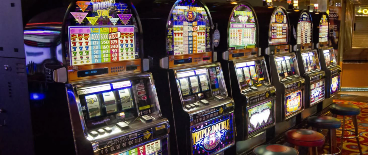 This is a picture of a row of slot machines within a slot hall. You can read more about online slots and you can find slot reviews (with a a video) below the picture.